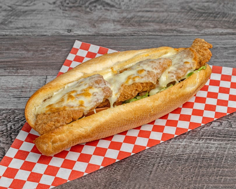 A crispy fried chicken sandwich with melted cheese and lettuce on a sub roll.